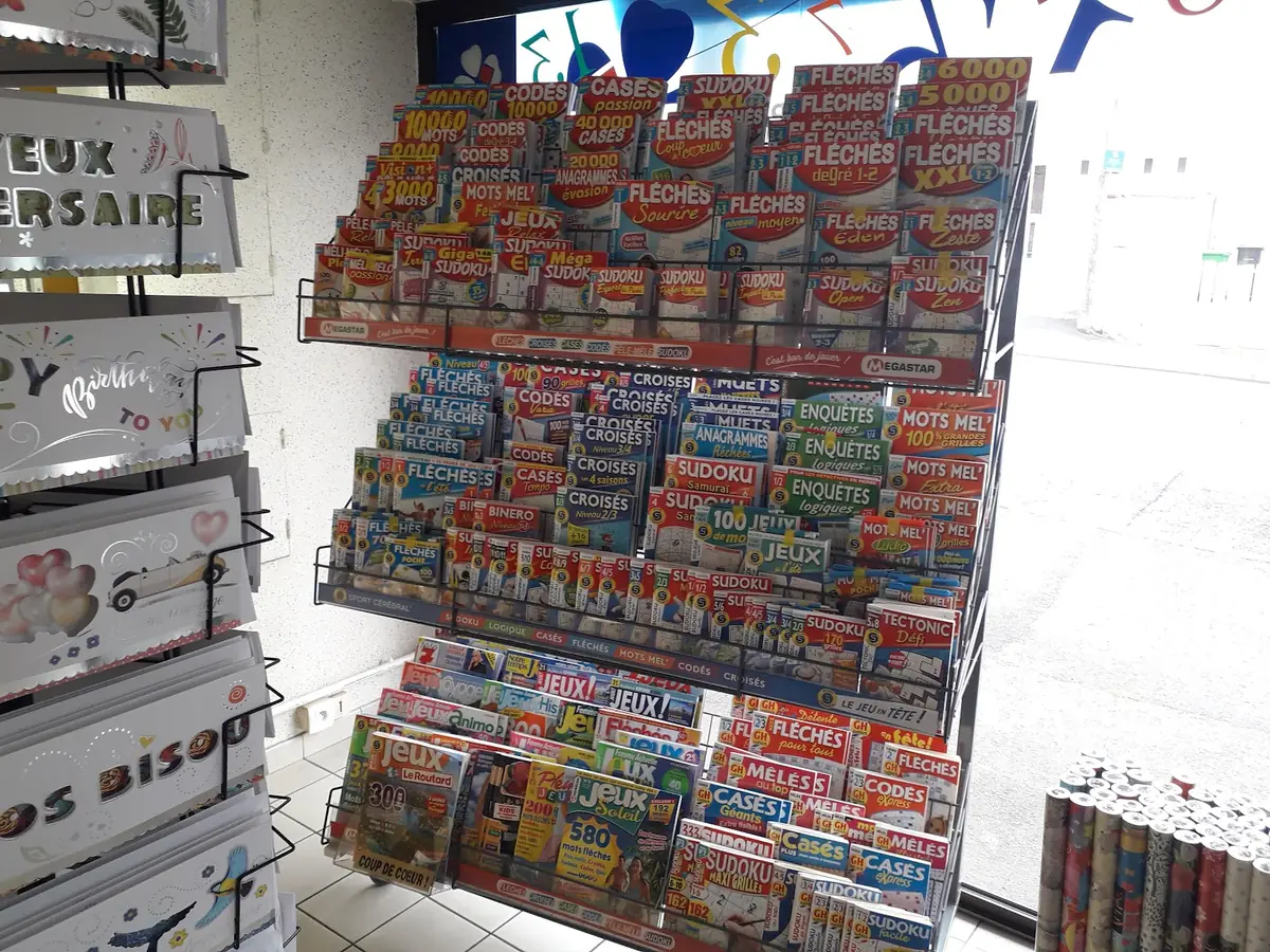 Le présentoir de magazines de mots fléchés et de sudoku, à côté des cartes d'anniversaire et des rouleaux de papier cadeau